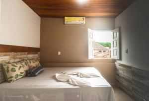 伦索伊斯Roncador Suítes的一间卧室配有一张带窗户的床