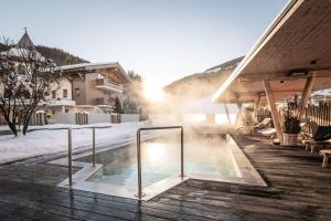 萨尔巴赫索奈格酒店的房屋旁的雪地里有一个热水浴缸