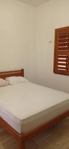 弗雷谢拉斯Casa Tropicana的一间卧室配有一张带白色床单的床和一扇窗户。
