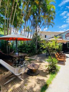 瓜鲁雅Tombo Beach Hostel & Pousada的庭院配有桌椅和遮阳伞。