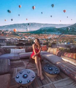 格雷梅Caravanserai Inn Hotel的穿着红色衣服的女子坐在带热气球的舱底上