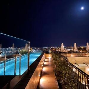 瓦莱塔The Gomerino Hotel的一座游泳池,在晚上在一座建筑的顶部