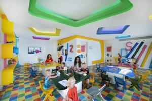 赫尔格达Pickalbatros Aqua Blu & Vista Resort - Hurghada的一群坐在游戏室的桌子上的孩子