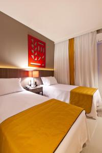 塞蒂拉瓜斯San Diego Suites Veredas Sete Lagoas的酒店客房,设有两张床和红色的绘画