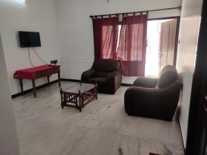 蓬蒂切里Villa Souhayl homestay的客厅配有两把椅子、一张桌子和电视