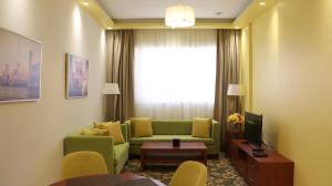 阿布扎比Al Riyadh Hotel Apartments的客厅设有绿色沙发和窗户。