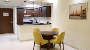 阿布扎比Al Riyadh Hotel Apartments的厨房配有木桌和黄色椅子