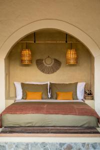 龙目岛库塔Drop In Surf Lodge的一间卧室配有带橙色枕头和2盏灯的床。