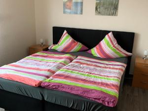 霍鲁梅尔希尔Gästehaus Vogel的床上配有色彩缤纷的毯子和枕头