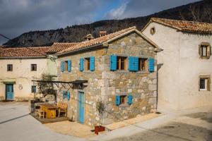 罗克Mountain Lodge Istria, Tiny house的一座古老的石头建筑,上面有蓝色百叶窗