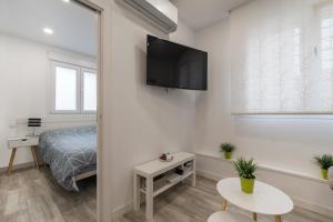 马德里4Torres Homes - Sofía的卧室配有一张床和壁挂式平面电视。