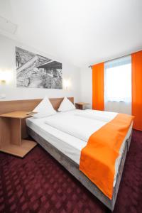 伍珀塔尔沃彼塔尔麦克乔姆斯酒店的一间卧室配有一张带橙色毯子的大床
