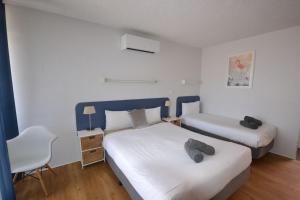 梅林布拉南海汽车旅馆的一间小卧室,配有两张床和椅子