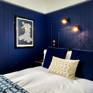 TrefriwCrafnant House - Bed & Breakfast的一间卧室设有蓝色的墙壁和一张带枕头的床