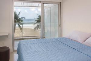 瓜鲁雅Asturias Mall & Suítes的一间卧室配有一张床,享有海滩美景
