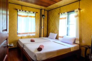 安帕瓦Baansuan Lychee Maeklong Resort Ampawa的带2扇窗户的小客房内的2张床