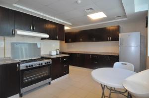 迪拜Elegance hostel的厨房配有木制橱柜和白色桌子。