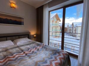 古多里New Gudauri Alpen Apartments的一间卧室设有一张床和一个大窗户