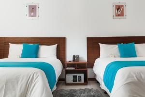 拉塔昆加REEC Latacunga by Oro Verde Hotels的两张带蓝色和白色床单的床