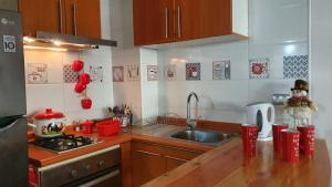 普孔Hermoso Departamento Full Equipado的厨房配有水槽和带红杯的吧台