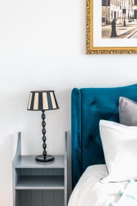埃尔布隆格Bea Home Elblag - dwie sypialnie的一张带蓝色床头板的床和一张带台灯的桌子