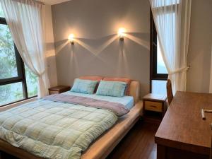 Kampong TengCA Homestay Borneo Highland的一间卧室配有带2个枕头的床和2个窗户。