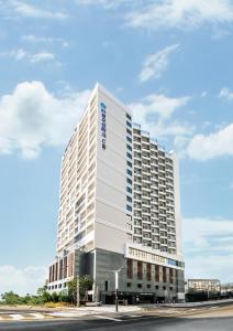 束草市Risen Ocean Park Hotel的上面有蓝色标志的高大的白色建筑
