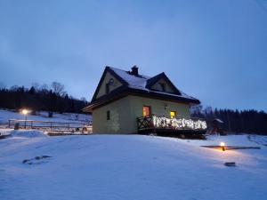 斯托尼拉斯奇Górskie Zacisze Kamienica的雪中的房子,上面有灯