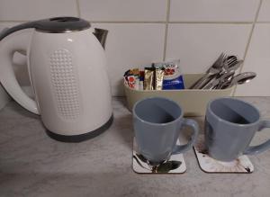 韦尔科姆Floret Cottage的柜台上放两个咖啡杯和茶壶