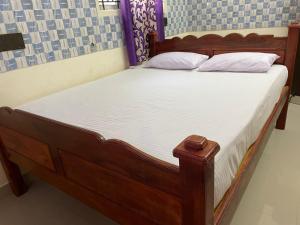 坦贾武尔Sarah Residency的一张带白色床单和枕头的木床