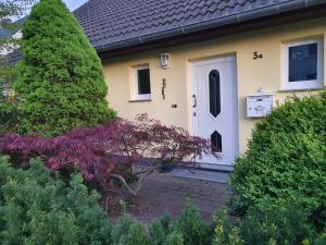 MönchhagenHeideperle3a的黄色的房子,有白色的门和灌木丛