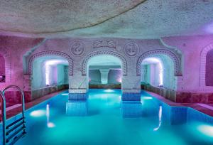 内夫谢希尔Cappadocia Ennar Cave Swimming Pool Hot & SPA的游泳池拥有粉红色的墙壁和蓝色的水
