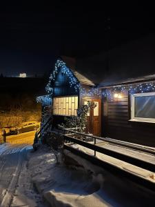 SłotwinyDomek nad Potokiem的雪中带圣诞灯的房子