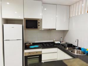 普拉亚Apto Morabeza T2 Praia的厨房配有白色橱柜和白色冰箱。