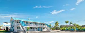 迈尔斯堡海滩Latitude 26 Waterfront Resort and Marina的酒店建筑拥有蓝色的屋顶和棕榈树
