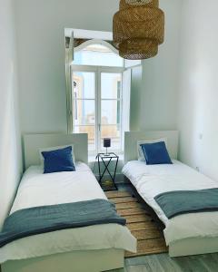奥良Casa Cubista的带窗户的客房内的两张床和蓝色枕头
