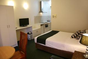 墨尔本福特斯克瑞汽车旅馆加服务式公寓酒店的一间卧室配有一张床和一张书桌及电视