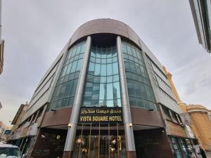 迪拜Vista Square Hotel的一座大型玻璃建筑,设有步行广场