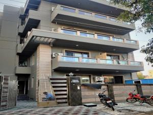 古尔冈BluO 2BHK Golf Course Road, Balcony, Lift, Parking的两辆摩托车停在楼前的建筑物