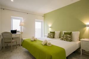 里斯本Suites Amália Guesthouse near Rossio Square的一间卧室配有一张带绿毯的大床
