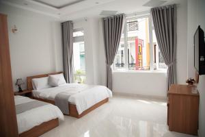 大叻Peony Hotel的一间卧室设有两张床和窗户。