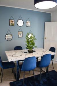 科尔切斯特The Velveteen Townhouse的一间带桌子和蓝色椅子的用餐室