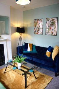 科尔切斯特The Velveteen Townhouse的客厅配有蓝色的沙发和玻璃桌