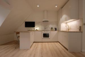 巴登-巴登查尔梅精品公寓的一间厨房,配有白色橱柜和墙上的电视