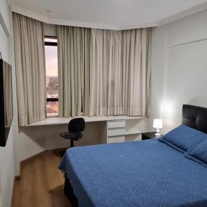 坎皮纳斯Flat Centro Campinas - L'Hirondelle 125的一间卧室设有蓝色的床和窗户。