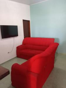 乌巴图巴Casa pé na areia的客厅设有一张红色沙发,配有电视