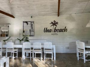 乌纳瓦图纳Una Beach Hotel & OLU Cafe的一间设有白色桌子和白色椅子的用餐室