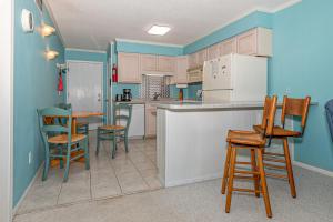 大西洋滩Seaspray的厨房拥有蓝色的墙壁和木制椅子