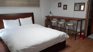 西归浦市城山友利大厦度假屋的卧室配有白色的床、桌子和凳子。