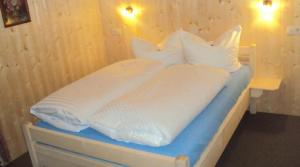 加尔盖伦Pension Sursilva的一张带白色床单和枕头的床